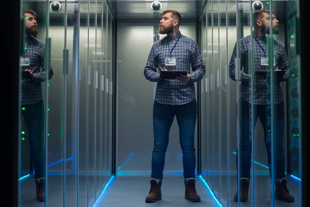 man inspecting servers in server room - 2023 Cyber Security Challenges concept image